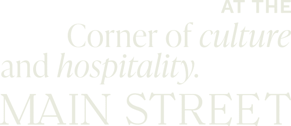 Text reads: "At the corner of culture and hospitality management. Main Street." The text is in bold sans-serif and italic fonts on a green background.